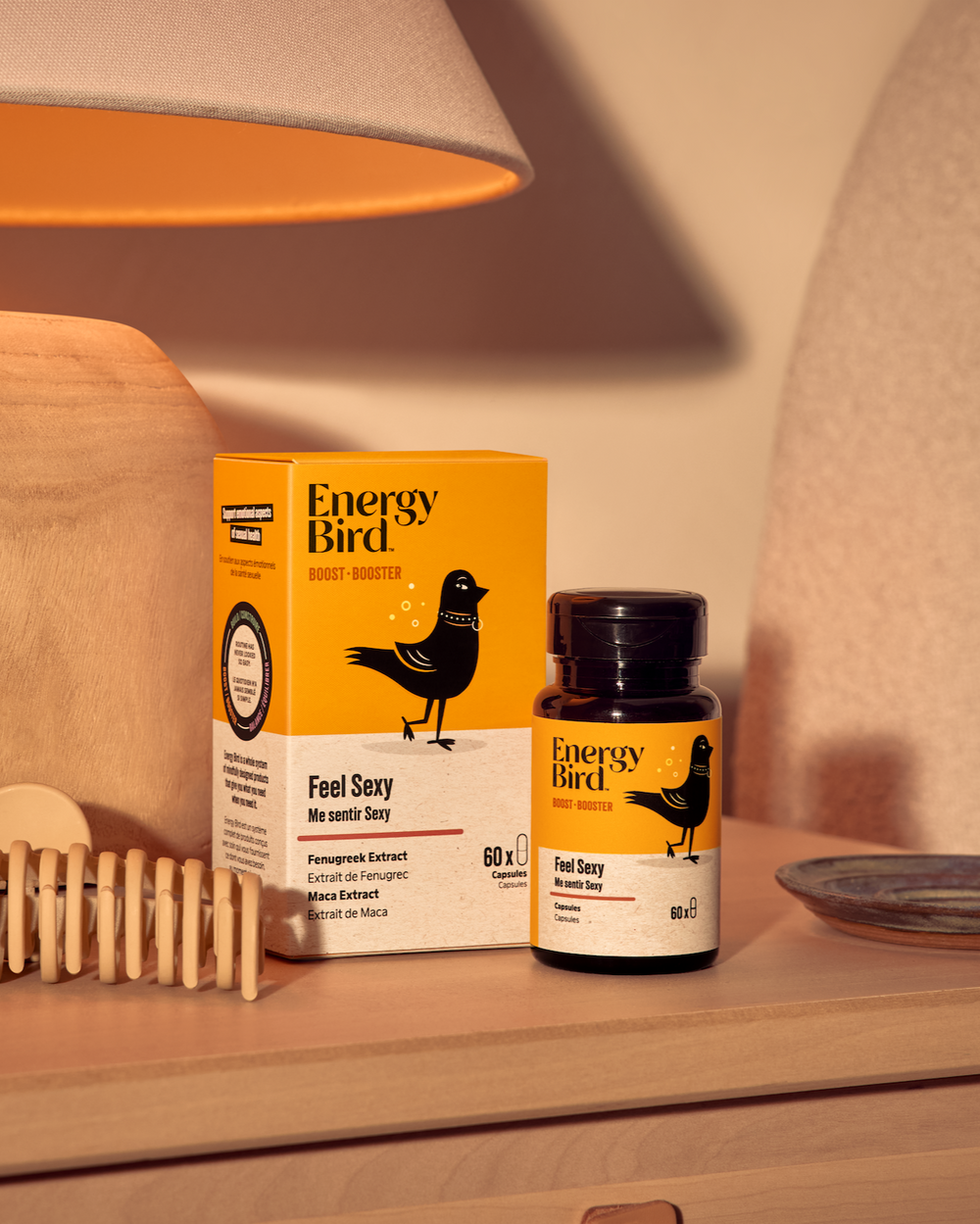 Emballage et flacon Me sentir sexy par Energy Bird sur une table de nuit à côté d'une lampe