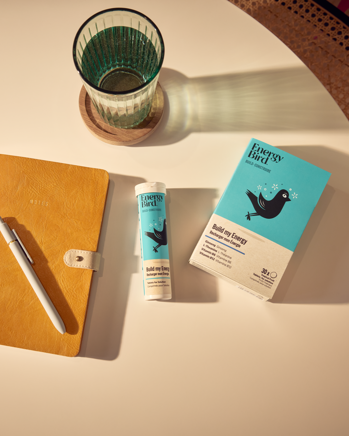 Energy Bird's Build My Energy Packaging on a table beside a notebook and glass of water