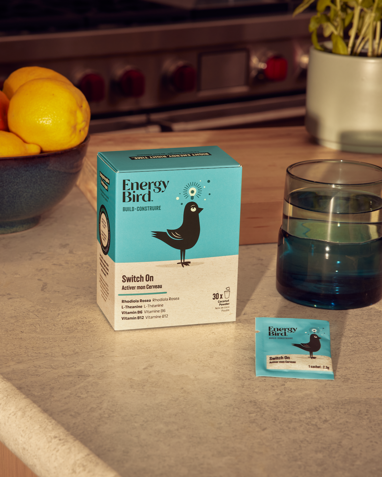Energy Bird's Switch On on a kitchen counter beside a glass of water and bowl of lemons