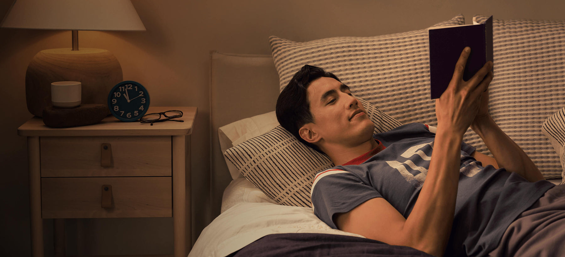 Man lying in bed reading a book.