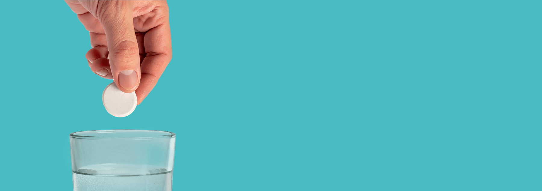 Person putting build my energy tablet into a glass of water